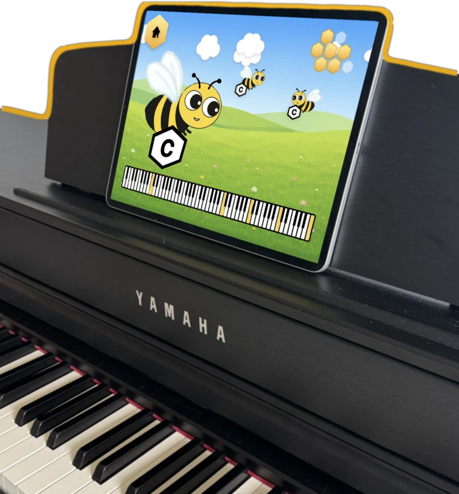 An iPad propped on the music desk of a Yamaha digital piano, running Bees Keys: a bee carries a hexagon marked C above an on-screen keyboard, with the piano's real keys below.